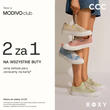 dziewczyna w szortach, widziana od pasa w dół, trzyma kilka par butów 